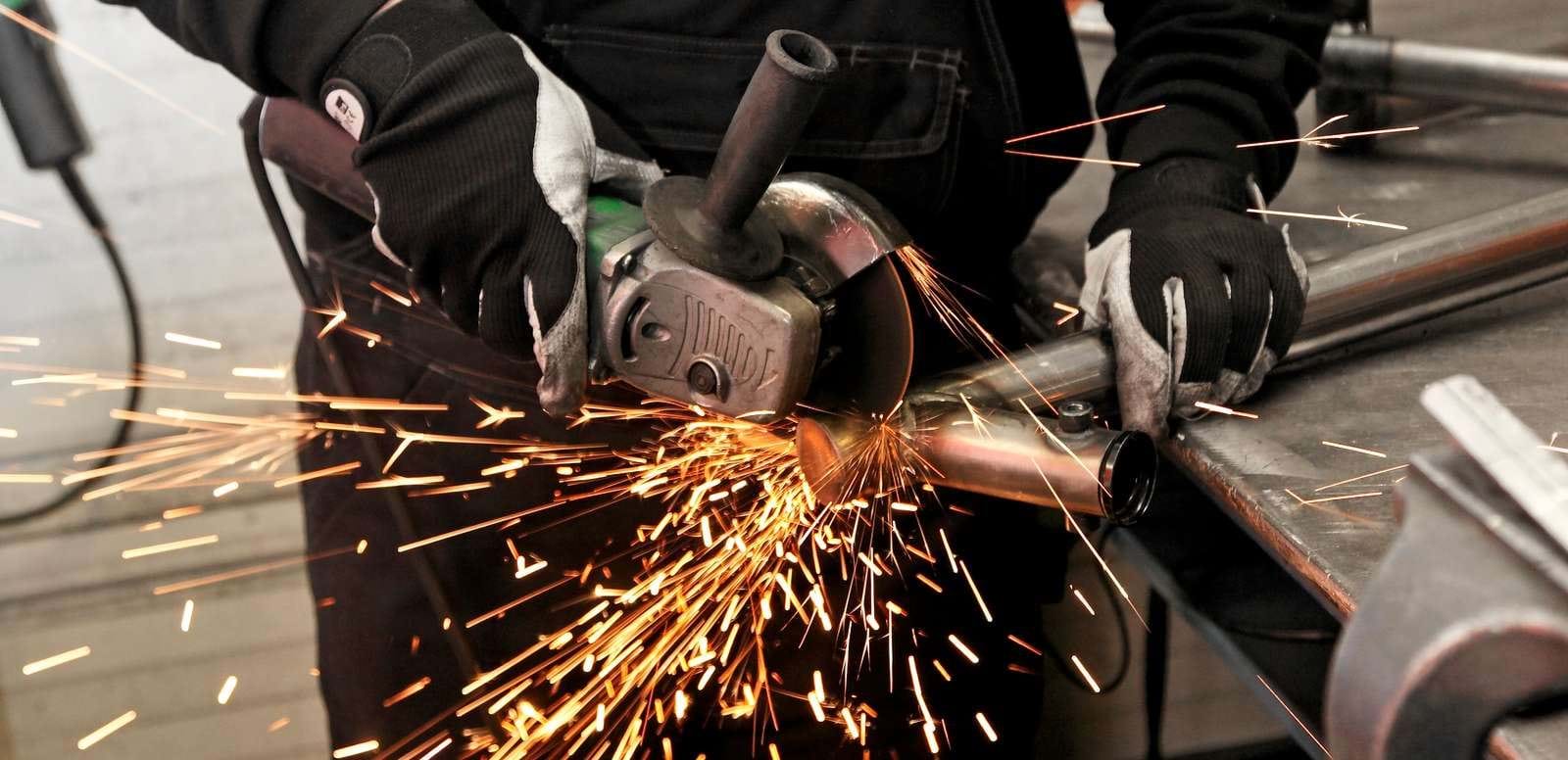 Person med vinkelsliber skærer i metal