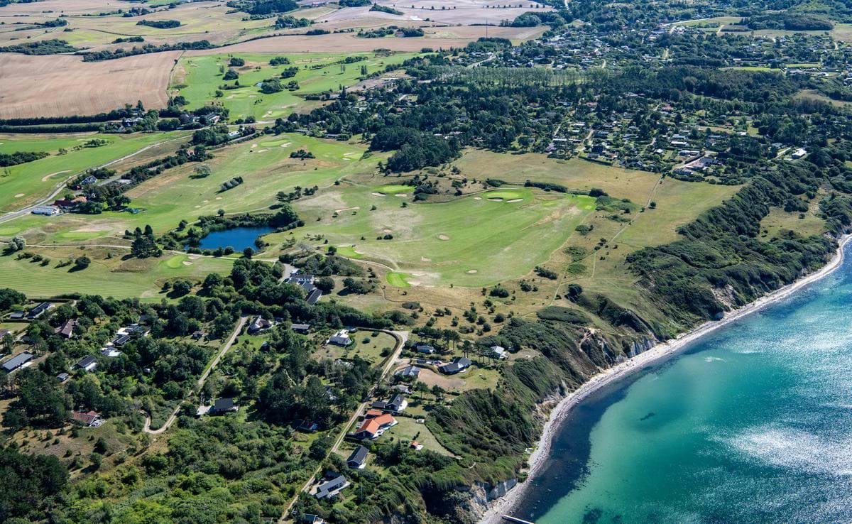 Luftfoto af en kystlinje i Kalundborg. Der ses en golfbane og sommerhusområder langs kysten.